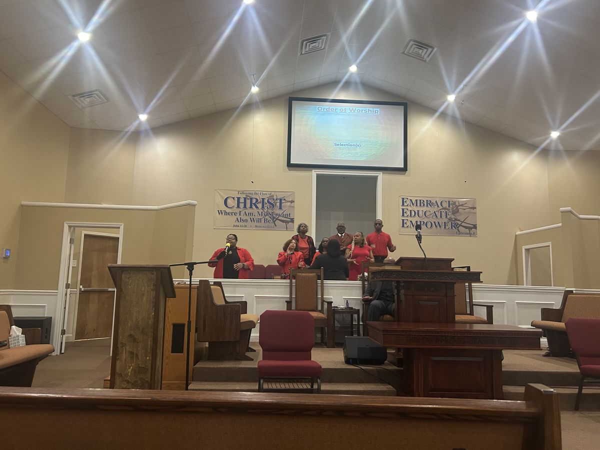 The choir, dressed in red, singing at the front of the sanctuary