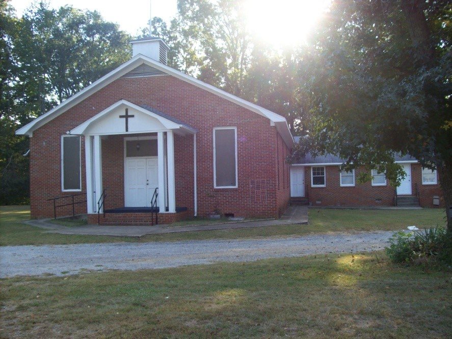 Flint River's red brick church building among trees